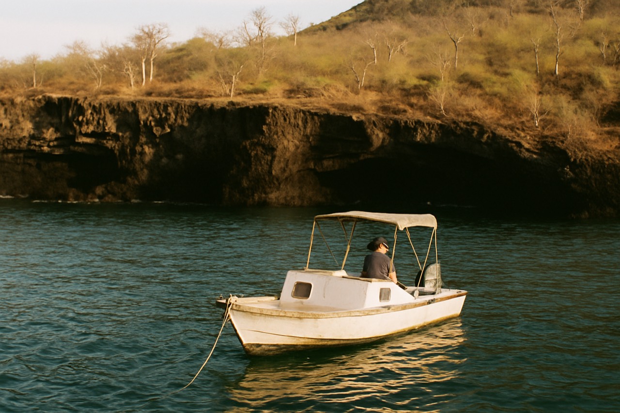 A small boat anchored near a rocky Galapagos shoreline with clear turquoise water