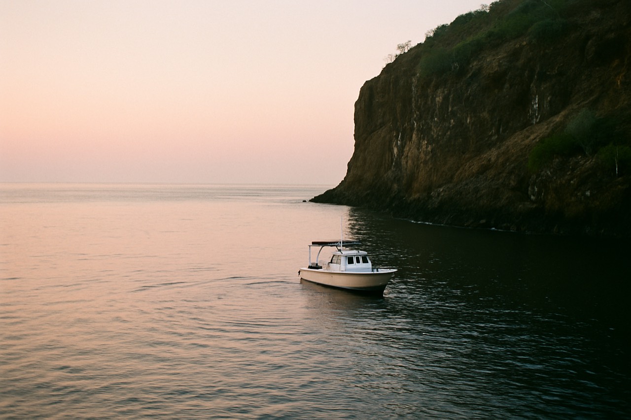 A small dive boat anchored near a rocky Galapagos shoreline at dawn
