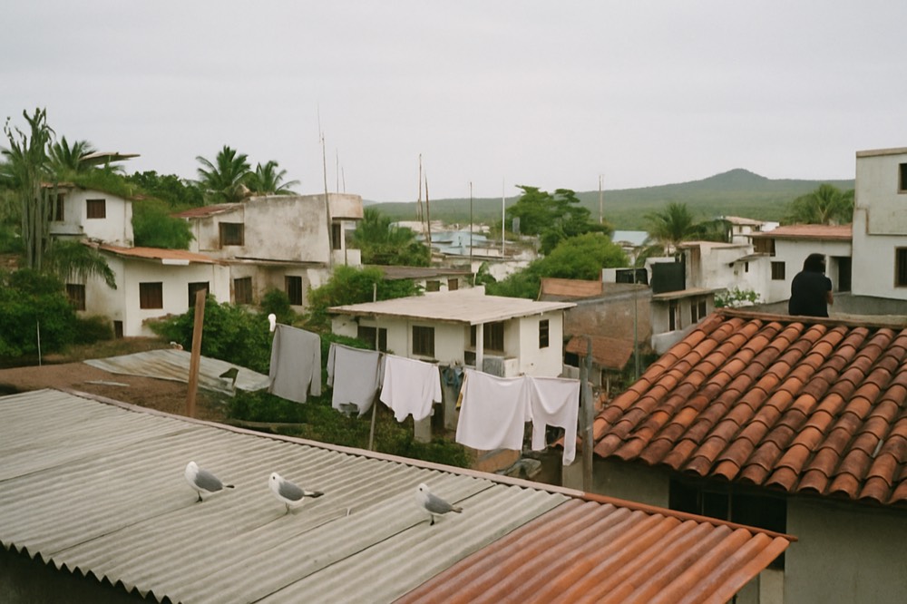 A city skyline of mountains and tiled rooftops under morning clouds