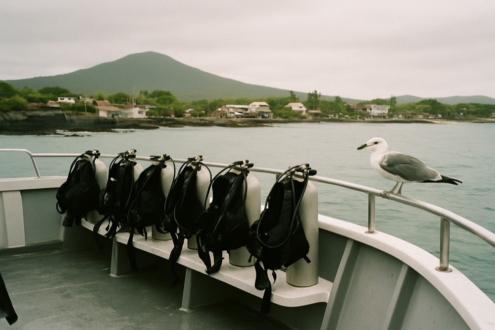 Divers preparing gear on the deck of a small boat near a Galapagos island